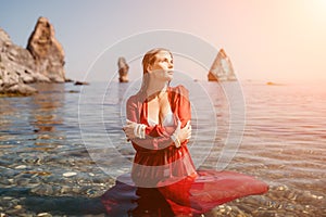 Woman travel sea. Happy tourist in red dress enjoy taking picture outdoors for memories. Woman traveler posing in sea