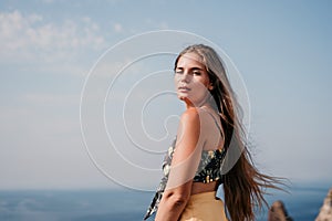 Woman travel sea. Happy tourist taking picture outdoors for memories. Woman traveler looks at the edge of the cliff on