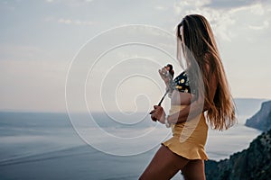 Woman travel sea. Happy tourist taking picture outdoors for memories. Woman traveler looks at the edge of the cliff on
