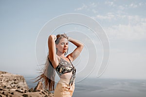 Woman travel sea. Happy tourist taking picture outdoors for memories. Woman traveler looks at the edge of the cliff on