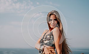 Woman travel sea. Happy tourist taking picture outdoors for memories. Woman traveler looks at the edge of the cliff on