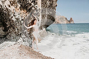 Woman travel sea. Sporty happy middle aged posing on a beach near the sea on background of volcanic rocks, like in