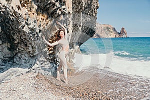 Woman travel sea. Sporty happy middle aged posing on a beach near the sea on background of volcanic rocks, like in