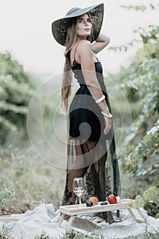Woman travel winery. Portrait of happy woman holding glass of wine and enjoying in vineyard. Elegant young lady in hat