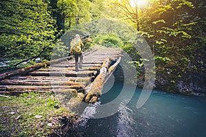 Woman Traveler with backpack hiking on bridge over river