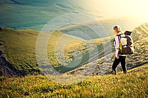 Woman Traveler with Backpack hiking in Mountains