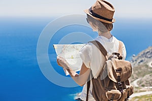 Woman traveler with backpack holding map. Travel, tourism, summer holidays, active lifestyle concept. Hipster tourist girl looking