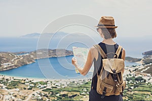 Woman traveler with backpack holding map. Travel, tourism, summer holidays, active lifestyle concept. Hipster tourist girl looking