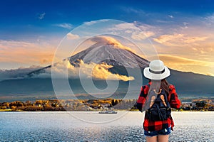 Woman traveler with backpack looking to Fuji mountains at sunset in Japan.