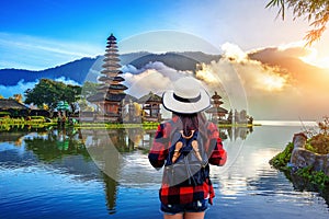 Woman traveler with backpack looking to pura ulun danu bratan temple in Bali, indonesia.