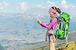 Woman traveler with a backpack and a map on the background of the Pyrenees mountains. Hiking and adventure concept
