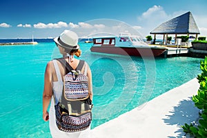Woman traveler with backpack near boat at tropical island