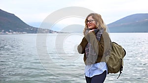 Woman traveler with a backpack is standing on the sea coast