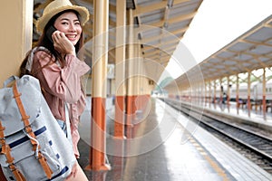 Woman traveler with backpack talk on mobile smart phone at train station. trip journey travel concept