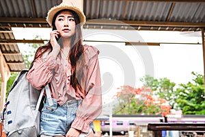 Woman traveler with backpack talk on mobile smart phone at train station. trip journey travel concept