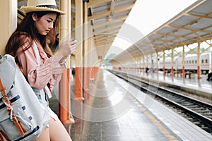 Woman traveler with backpack use mobile smart phone at train station. trip journey travel concept