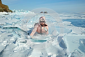 A woman traveler behind a transparent ice floe of frozen Lake Baikal.