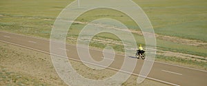 The woman traveler on bike on an asphalt winding road. The picturesque top view. The girl journey on touring bike with