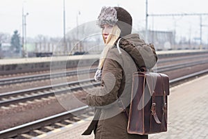 Woman traveler with brown leather rucksack waiting train