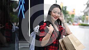 Woman traveler carrying shopping bags and walking in city street.