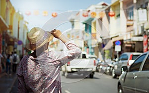 Woman traveler in casual dress walking in thalang road with blurred chino portuguese style building