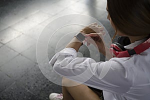 Woman traveler checking time on her wristwatch at rail station platform.