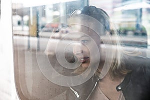 Woman traveler contemplating outdoor view from window of train. Young lady on commute travel to work sitting in bus or