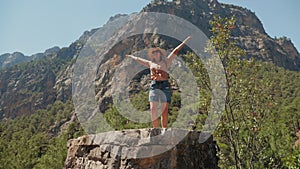 Woman traveler enjoying the mountains while standing on top of the cliff