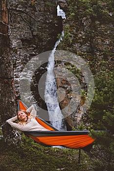 Woman traveler enjoying waterfall view chilling in hammock travel lifestyle in Norway active summer vacations