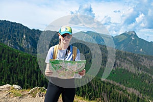 Woman traveler explorer with backpack hiking to the top of the mountain.Shot of a young lost woman holding a map while