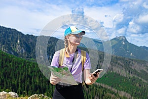 Woman traveler explorer with backpack with phone hiking to the top of the mountain.Shot of a young lost woman holding a