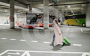 Woman traveler with ffp2 respirator going trough bus station with luggage. Traveling during covid pandemic. photo
