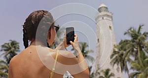 Woman Traveler in Front of Famous Landmark of Sri Lanka with smartphone, Dondra Lighthouse