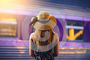 Woman traveler with hat near railroad tracks waiting for train