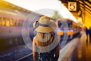 Woman traveler with hat near railroad tracks waiting for train