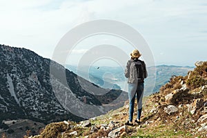 Woman traveler with a hat standing on a background of green mountains