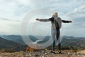 Woman traveler with a hat standing on a background of green mountains