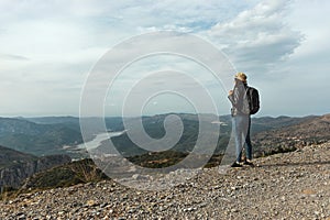 Woman traveler with a hat standing on a background of green mountains