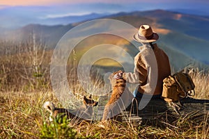 Woman traveler with her dogs enjoying sunset on peak of mountain.