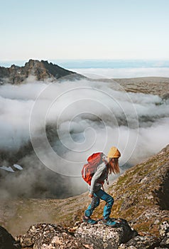 Woman traveler hiking with backpack above clouds travel outdoor climbing adventure vacation