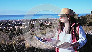 Woman Traveler Hiking on a Mountain Road with Map on a Sunny Summer Day