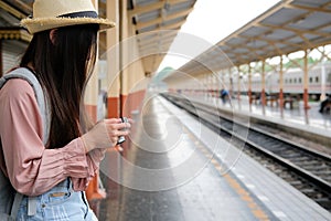 Woman traveler holding camera taking photo at train station. travel trip journey