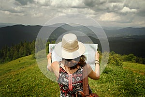 Woman traveler holding map and looking at it exploring on top of