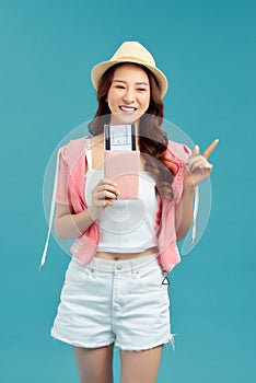 Woman traveler holding passport with ticket. Portrait of smiling happy girl on blue