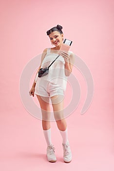 Woman traveler holding passport with ticket. Portrait of smiling happy girl on pink