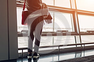 Woman traveler looking at window waiting for boarding on airplane in airport hall