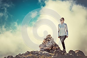 Woman Traveler on Mountain Summit with stones