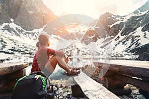 Woman traveler rests near mountain lake with beautiful view on s