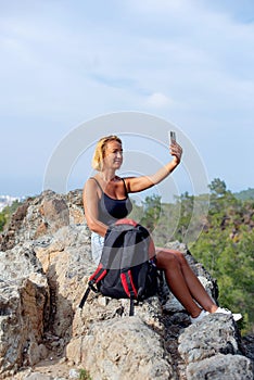 Woman traveler with rucksack on back searching information on mobile smart phone while relaxing , young stylish female watching