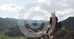 Woman traveler sits on top of mountain admires nature view with river in valley.